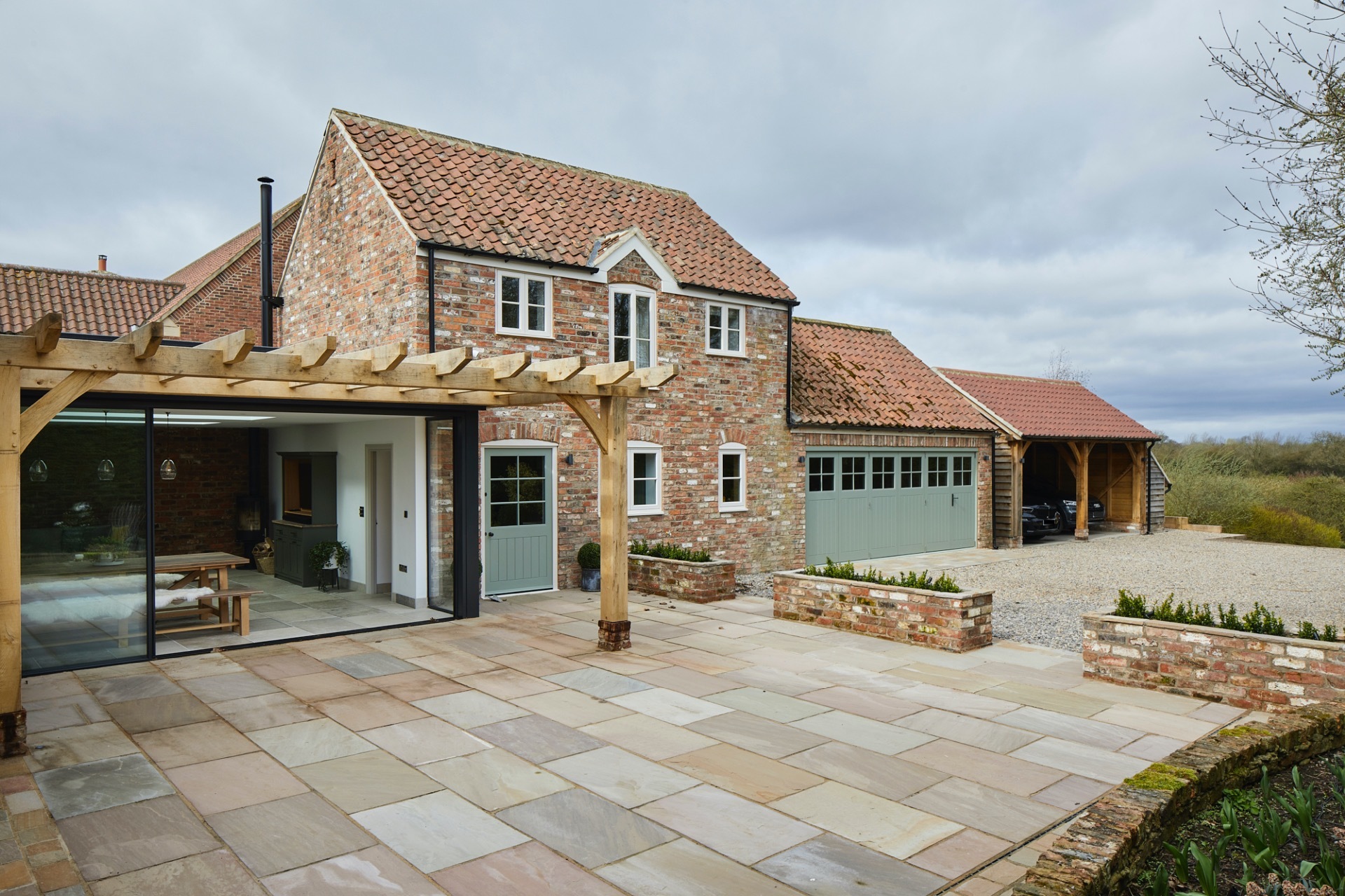 Completed external work including oak pergola, patio area & bespoke timber bifold doors to garage